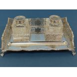 An Edwardian silver ink stand with pierced galleried sides, two cut glass ink bottles, pen well on