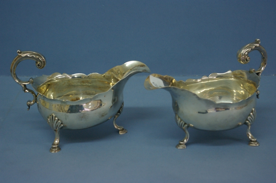 Pair of GIII silver sauce boats with shaped borders and scroll handles on hoof feet. London 1766. 14