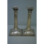 Pair of GV loaded silver column candlesticks with decoration of swags, on square bases. Sheffield