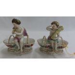 Pair of Meissen style porcelain bonbon dishes in the form of putti, each sitting on the edges of two