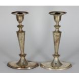 A pair of silver candlesticks by William Hutton & Sons Ltd, with plain decoration and loaded oval