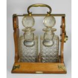 A two division oak and brass mounted tantalus by Betjemann, with a pair of cut glass decanters and