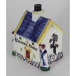 An early 19th century Staffordshire pottery money box shaped as a cottage, flanked by male and