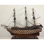 A good quality painted wooden model of HMS Victory, fully-rigged with sails furled, raised on wooden