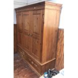 A pine triple wardrobe, the shaped cornice with dentil moulding, above three panelled doors