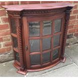 A bow-front mahogany wall hanging cabinet, the single glazed door enclosing shelves and flanked by