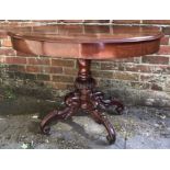 A mahogany oval table, with quarter veneered top, raised on carved and turned support to scrolled,