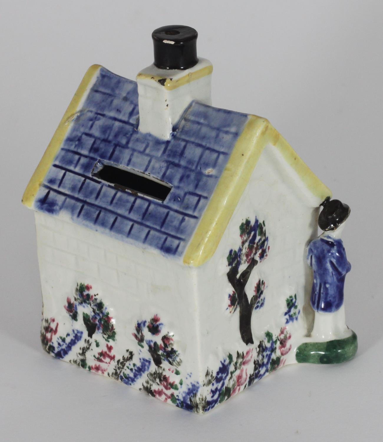 An early 19th century Staffordshire pottery money box shaped as a cottage, flanked by male and - Image 2 of 2