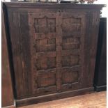 An Indian hardwood two-door store cupboard, 18th century heavily carved doors with iron ring pulls