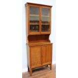 A mahogany bookcase, the shaped cornice above a pair of glazed doors enclosing shelves, leading to