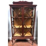 An Edwardian stained walnut two-door display cabinet, with trellis glazed doors and bevelled