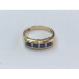 An 18ct yellow gold, sapphire and diamond ring, channel set with 4x princess-cut sapphires and 5x