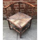 An Edwardian mahogany corner chair, with carved lyre backs and rush seat, raised on turned