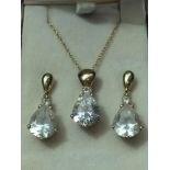 A matching white crystal pendant and earring set. The crystals are in a pear-shaped cut with a small