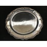 A continental .900 grade silver salver with planished inner rim and shaped outer edge,