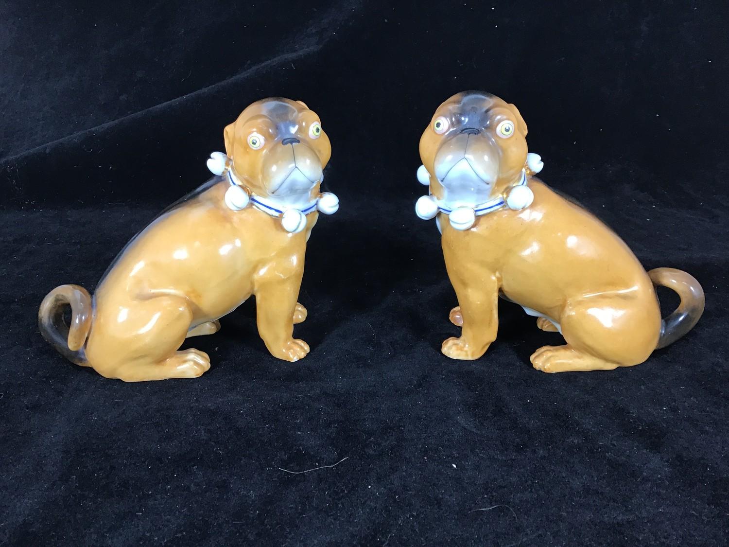 A pair of late 19th / early 20th century porcelain seated pugs with bell collars, in the style of