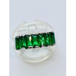 A ladys 18ct white gold-plated dress ring set with seven rectangular shaped green stones.