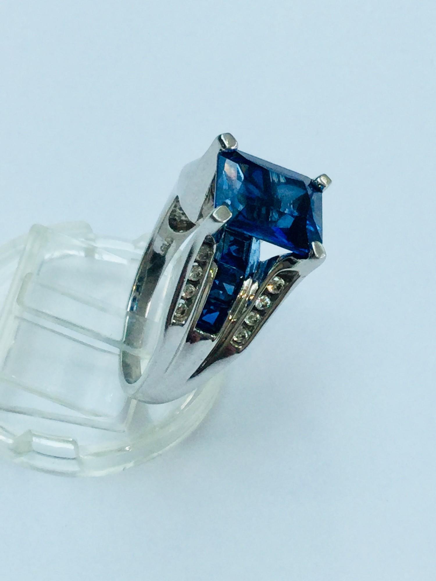 A ladys 10ct gold ring set with an emerald cut sapphire to the centre. Under the bezel is set 7 x - Image 2 of 3