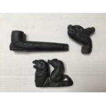 Three black jet stone carvings, comprised of a pipe and two wild animals, one ridden by figure of