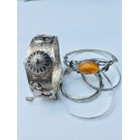 A mixed lot of silver bangles, consisting of one art nouveau style with an oval amber set to the
