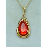 A 14ct yellow gold pendant and chain. The pendant is set with a pear shaped orange coloured stone