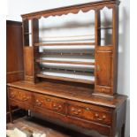An 18th century oak kitchen dresser, the open shelved back with shaped frieze, open shelves,