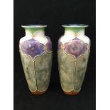 A pair of early 20th century Royal Doulton vases with tube-lined panels of purple and green with