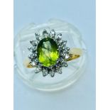 A ladys 18ct yellow gold Peridot and Diamond cluster ring. The oval peridot measuring 9mm x 6mm is