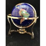 A hard stone globe with inlaid semi-precious stones to blue ground, raised on gilt rotating stand