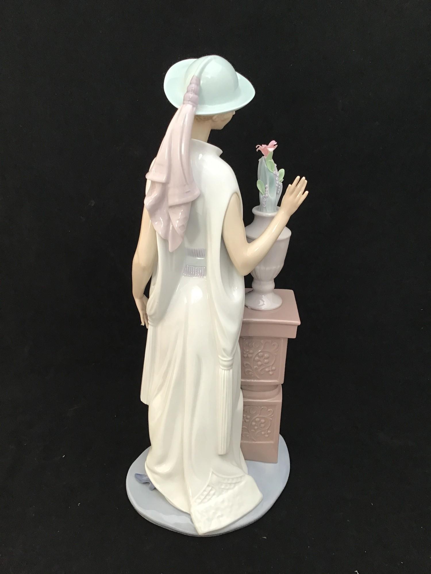 A large Lladro figurine of a lady in a long flowing dress and hat looking at a vase of flowers on - Image 3 of 3