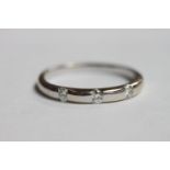 An 18ct white gold ring, the top rub over set with three diamonds, estimated total diamond weight