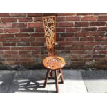 An oak Welsh spinning stool, with floral carved seat and back and pierced love heart to top of