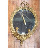 A Victorian oval gilt and gesso girandole mirror, ornately decorated with flowers, 73cm high
