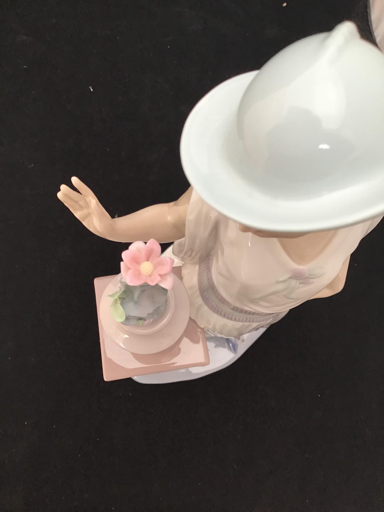 A large Lladro figurine of a lady in a long flowing dress and hat looking at a vase of flowers on - Image 2 of 3