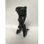 A bronze sculpture modelled as a female on her knees, removing her top, 26cm tall