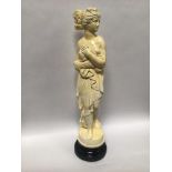 A painted plaster figure of a semi-clad classical maiden with hair up looking left, raised on