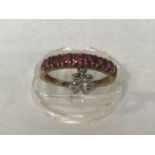 A 9ct gold ring channel set with ruby coloured stones and an attached white metal butterfly charm,