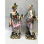 A pair of 19th century large Meissen porcelain figures in rococo style dress, one of a lady carrying