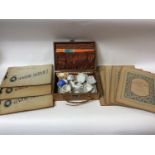 A miniature porcelain teaset in sued suitcase, together with various filled and empty cigarette card