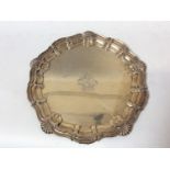 An Edwardian silver salver, with shell-capped scrolling serpentine rim, the centre engraved with a