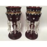 A pair of Victorian ruby glass lustres with scalloped edges, painted with floral swags and gilt