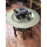A Middle Eastern two tier brass and wooden occasional table with scalloped edges, engraved with