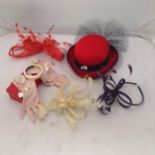 A collection of fascinators and accessories including a red hat with blue netting, pink gloves