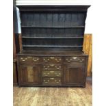 An 18th century and later oak dresser, with shelved and planked back, the base with three frieze