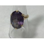 An 18ct gold ring claw set with an oval amethyst coloured stone measuring 2x1.5cm, gross weight 8.