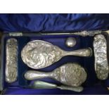 A silver-backed dressing set with scene of an Art Nouveau style maiden smelling flowers,