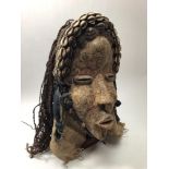 A Dan Deangle carved wooden tribal mask from the Ivory Coast, with seashell headband, plaited