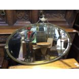 A 20th century oval Adam style bevelled wall mirror, brass frame surmounted with urn finial and