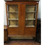 An Edwardian mahogany display cabinet, the shaped cornice above a pair of glazed doors enclosing