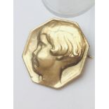 A 9ct yellow gold octagonal shaped brooch, featuring a raised childs head in profile, weighing 8.3